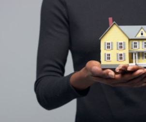 Cropped shot of a woman holding a miniature house